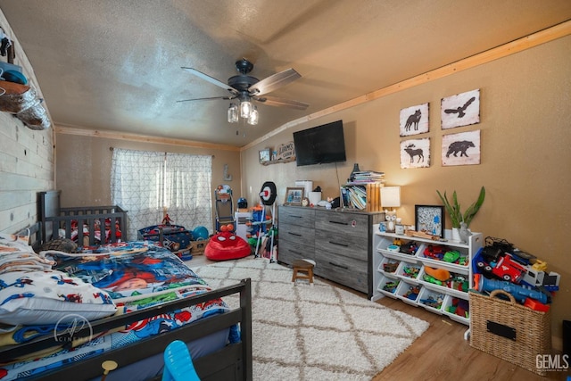 bedroom with ceiling fan, hardwood / wood-style flooring, a textured ceiling, and ornamental molding