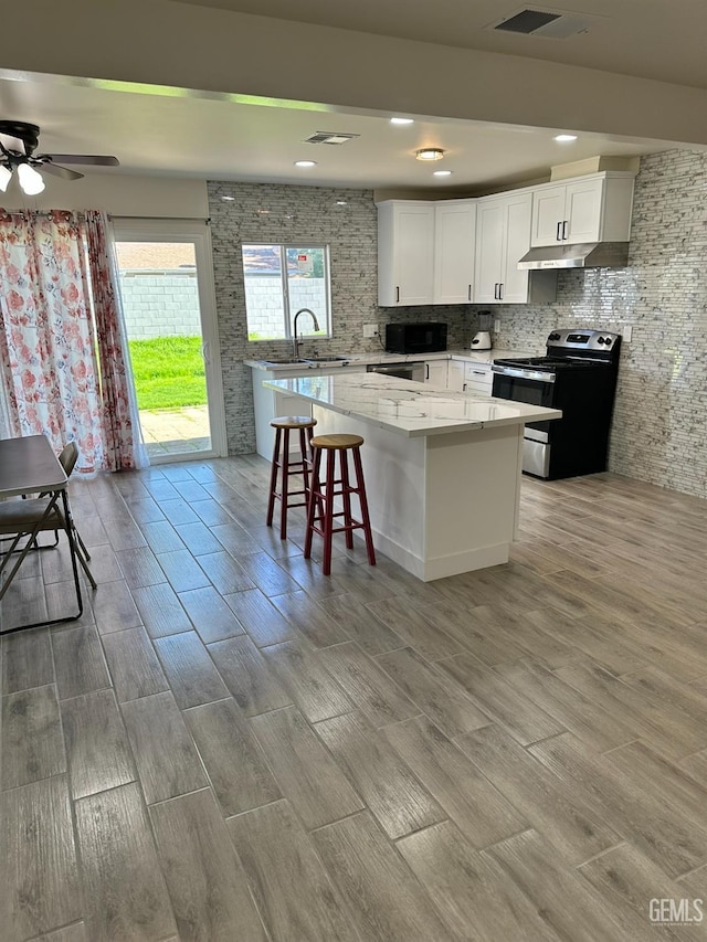 kitchen featuring a center island, a breakfast bar, electric range, sink, and white cabinetry