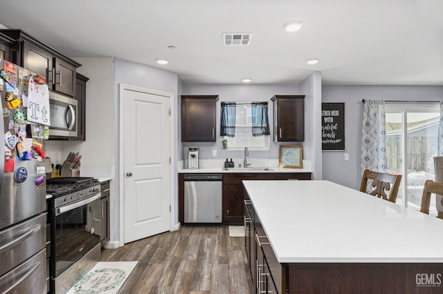 5803 Vespucci Ave, Bakersfield, CA 93313 - kitchen featuring stainless steel appliances, wood finished floors, dark brown cabinets, light countertops, and a kitchen island