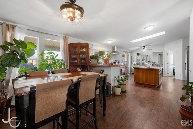 dining area with lofted ceiling with skylight, dark wood-style flooring, and ceiling fan