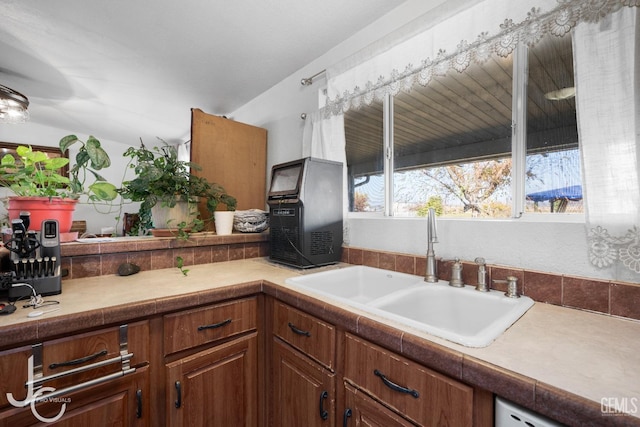 kitchen with dishwasher, light countertops, a sink, and brown cabinets