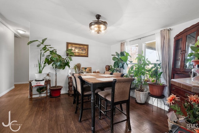 dining area featuring dark wood-style floors, lofted ceiling, and baseboards