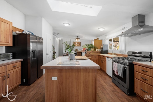 kitchen featuring stainless steel gas range oven, a skylight, fridge with ice dispenser, dishwasher, and wall chimney exhaust hood