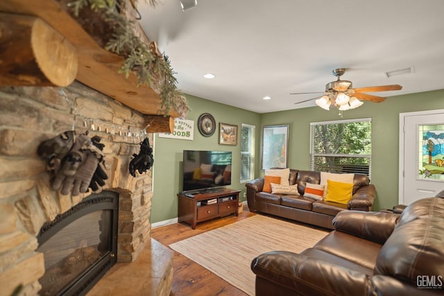 living room featuring ceiling fan, a fireplace, and light hardwood / wood-style flooring