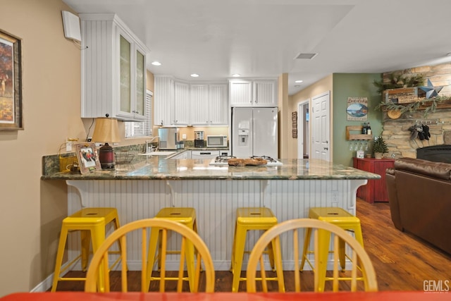 kitchen featuring kitchen peninsula, sink, white cabinets, and white refrigerator with ice dispenser