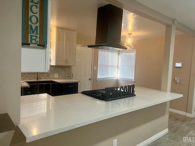 1312 Townsley Ave, Bakersfield, CA 93304 - kitchen with island range hood, black stovetop, white cabinets, tasteful backsplash, and baseboards