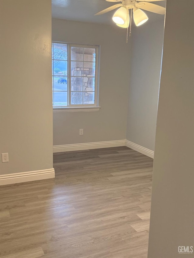 unfurnished room with baseboards, ceiling fan, and wood finished floors