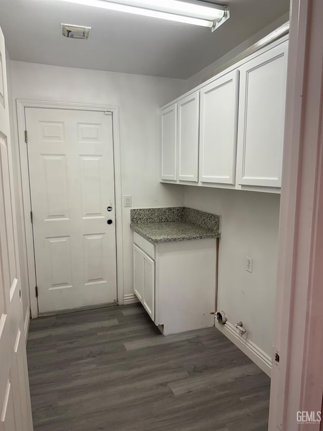 laundry area featuring cabinet space, dark wood-style flooring, baseboards, and visible vents