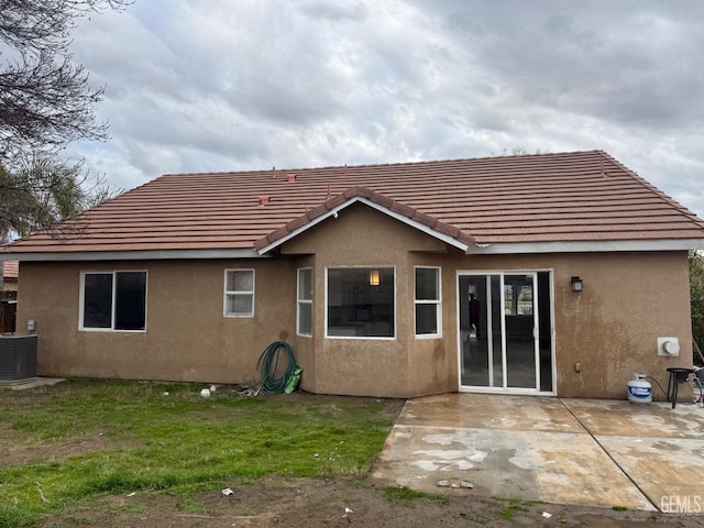 rear view of house with a tiled roof, a patio, central AC unit, and stucco siding