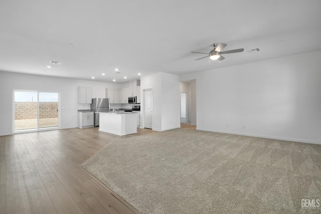 unfurnished living room with a ceiling fan, visible vents, baseboards, light wood finished floors, and recessed lighting