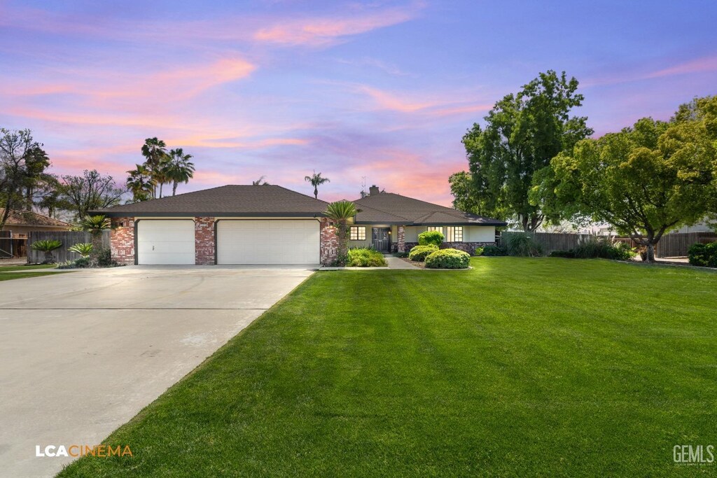 ranch-style home featuring concrete driveway, a garage, fence, and a front lawn