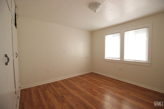 spare room featuring baseboards and wood finished floors