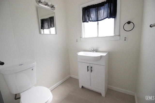 half bath with vanity, baseboards, tile patterned flooring, and toilet