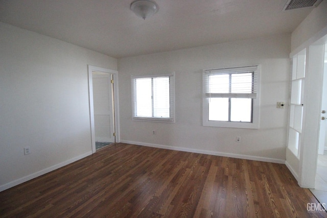 unfurnished room with dark wood-style flooring, baseboards, and visible vents