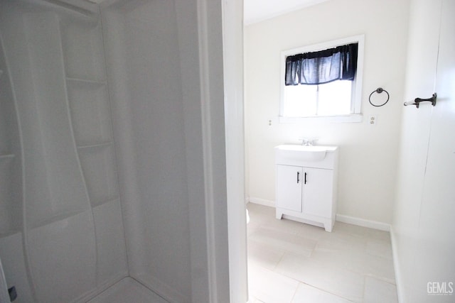 bathroom featuring tile patterned floors, baseboards, a shower, and vanity