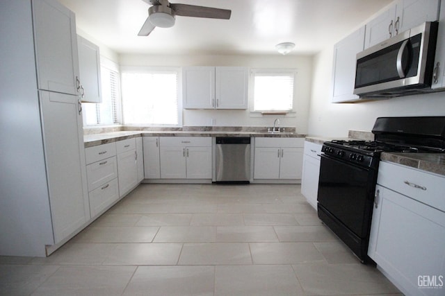 kitchen featuring a ceiling fan, light tile patterned flooring, white cabinets, a sink, and stainless steel appliances