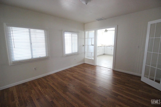 spare room with visible vents, baseboards, and wood finished floors
