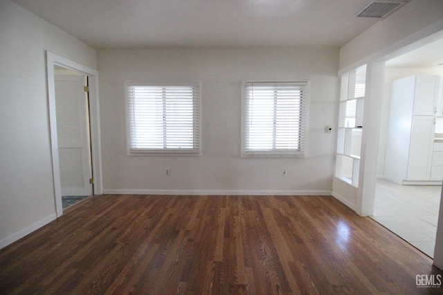 unfurnished room with visible vents, baseboards, and wood finished floors