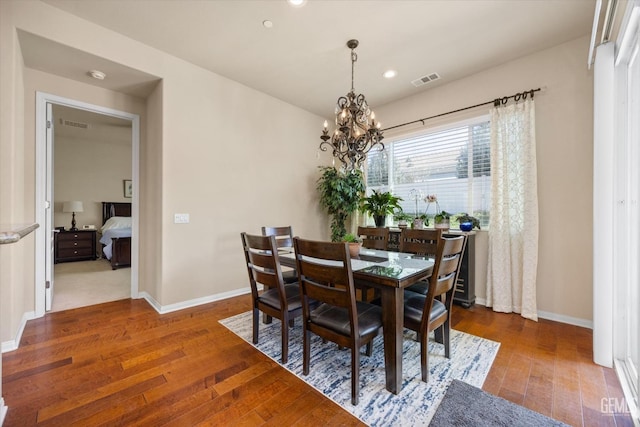 dining room with dark wood-style floors, visible vents, baseboards, and a notable chandelier