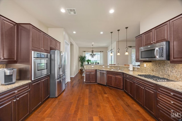 kitchen with light stone counters, dark wood finished floors, visible vents, hanging light fixtures, and appliances with stainless steel finishes