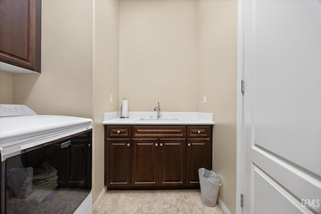 laundry room featuring washer / dryer, a sink, cabinet space, and baseboards