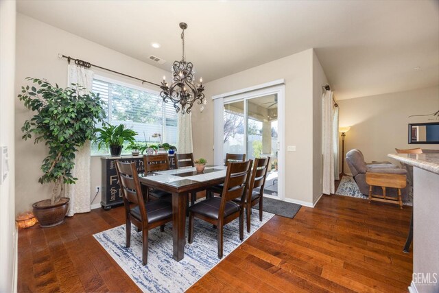 dining room with a healthy amount of sunlight, visible vents, dark wood finished floors, and a notable chandelier