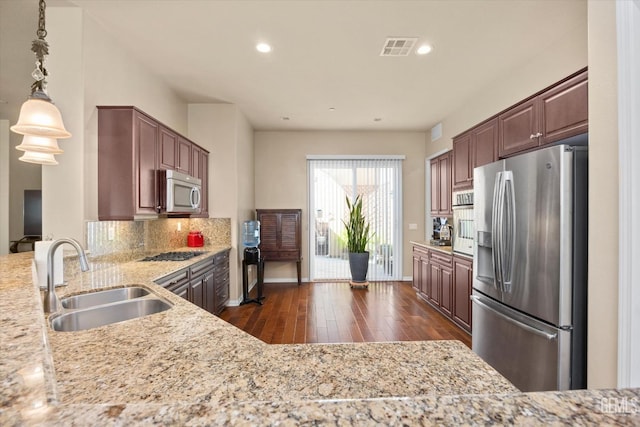 kitchen featuring visible vents, appliances with stainless steel finishes, light stone counters, hanging light fixtures, and a sink