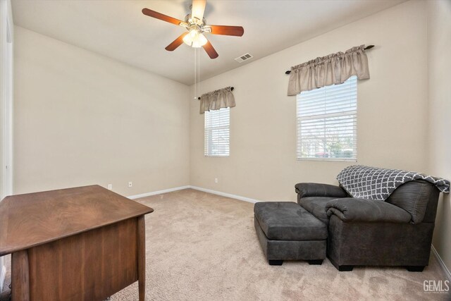 living area featuring light carpet, a ceiling fan, visible vents, and baseboards