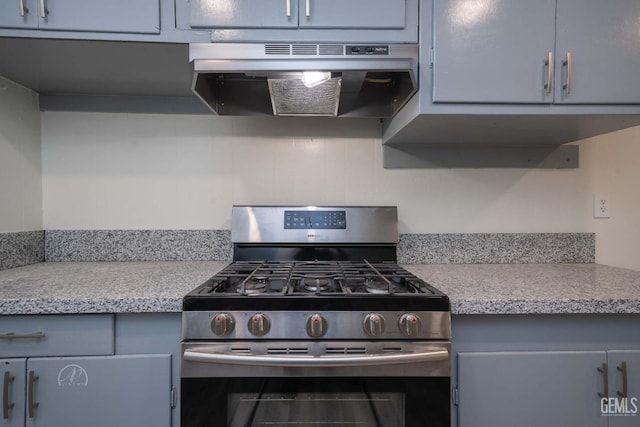kitchen with light countertops, gray cabinets, under cabinet range hood, and stainless steel gas range