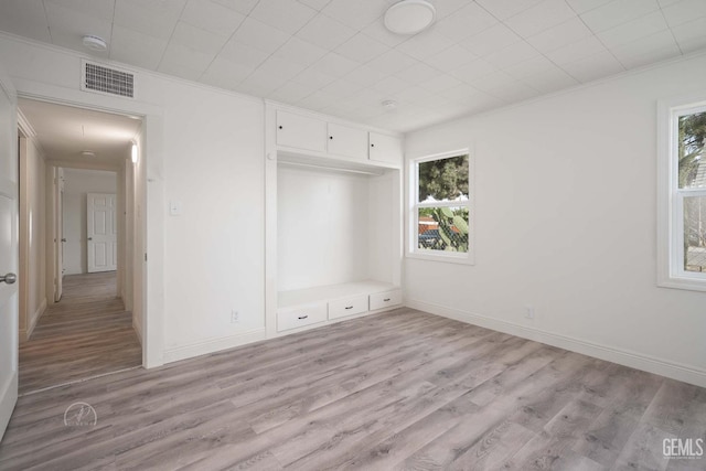 unfurnished bedroom with visible vents, ornamental molding, light wood-style flooring, and multiple windows