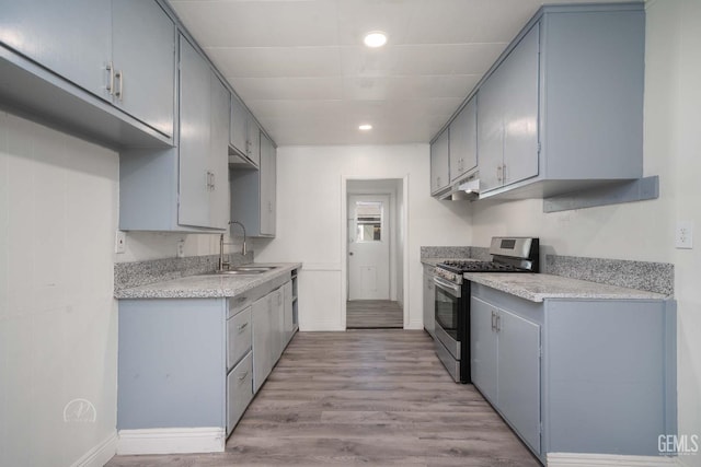 kitchen with baseboards, a sink, gas range, and light countertops