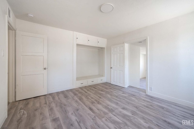 unfurnished bedroom featuring baseboards, light wood finished floors, and a closet