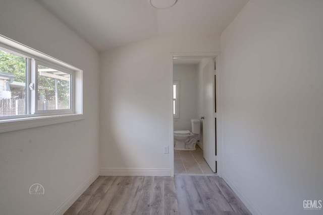 unfurnished bedroom featuring baseboards, ensuite bath, and light wood-style flooring
