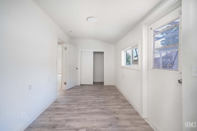 hallway with baseboards, light wood-type flooring, and lofted ceiling