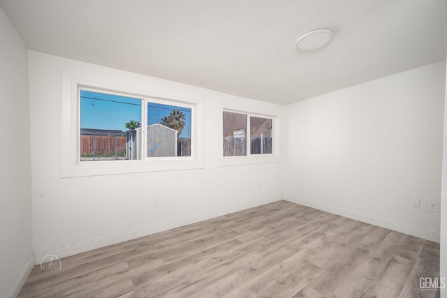 spare room featuring light wood-type flooring and baseboards