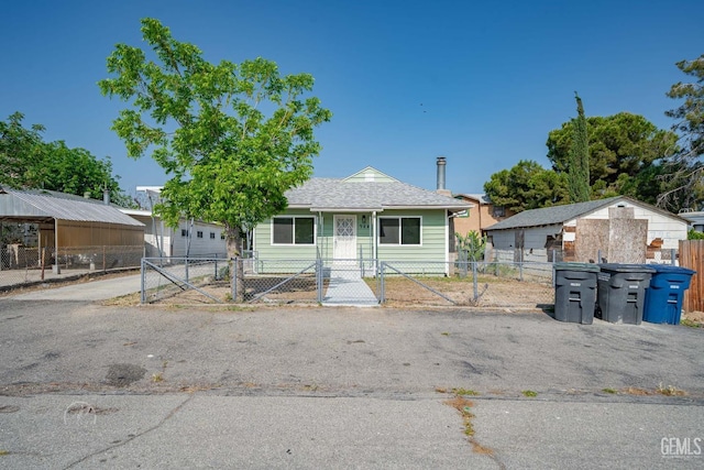bungalow featuring driveway, a fenced front yard, and a gate