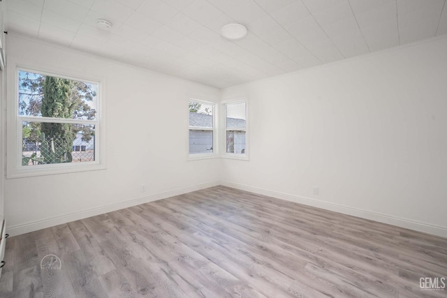 empty room featuring baseboards, ornamental molding, and wood finished floors