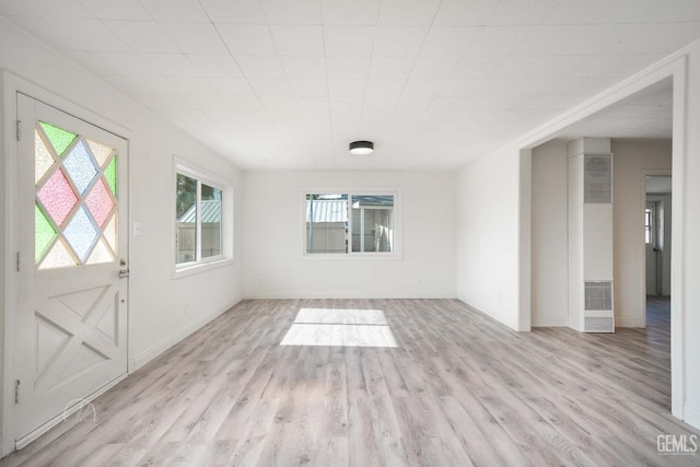 interior space featuring baseboards, wood finished floors, and a heating unit