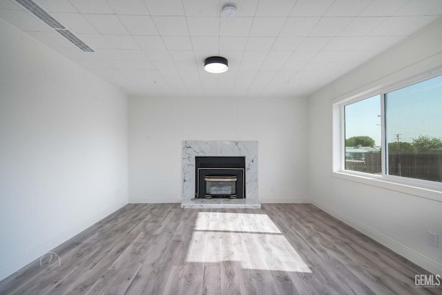 unfurnished living room with baseboards, wood finished floors, and a fireplace