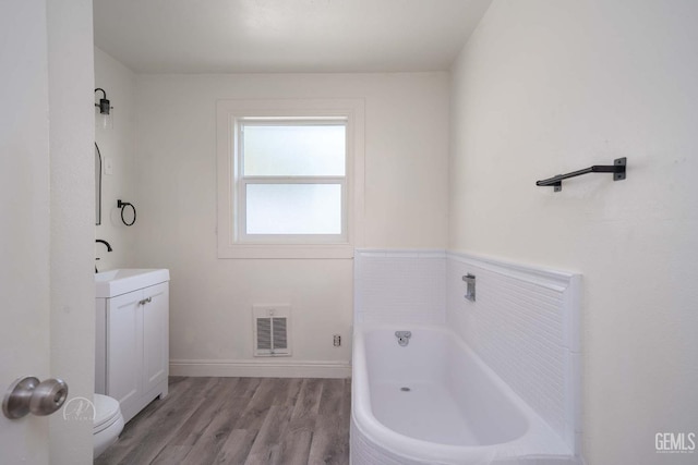 full bath featuring a bath, visible vents, wood finished floors, vanity, and toilet