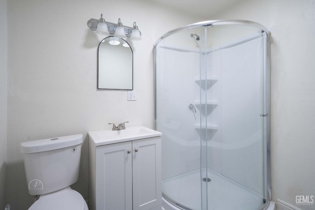 bathroom featuring vanity, a shower stall, and toilet