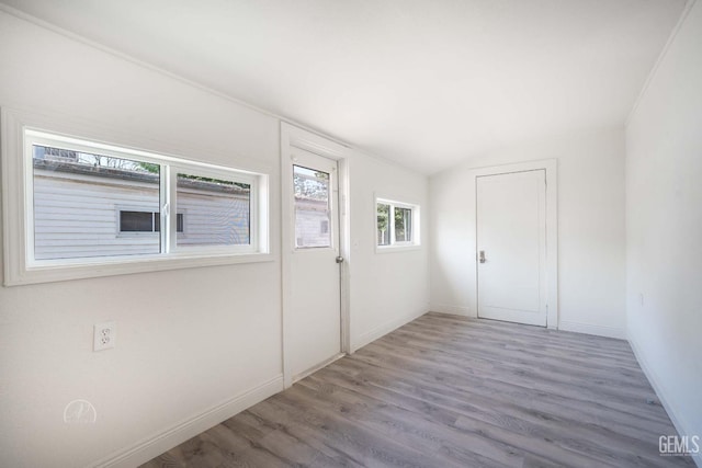 foyer featuring baseboards, wood finished floors, and vaulted ceiling