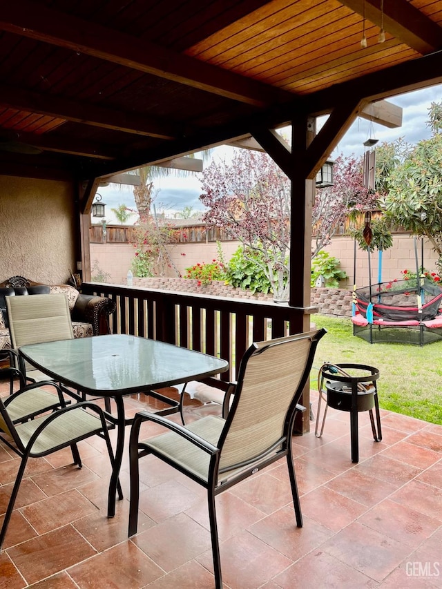 view of patio / terrace with outdoor dining space, a trampoline, and fence