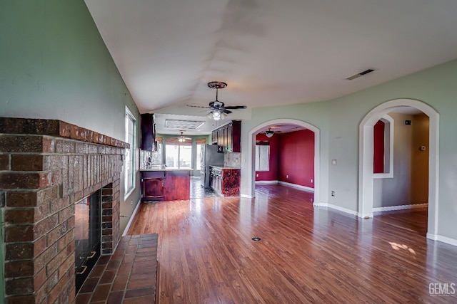 unfurnished living room with ceiling fan, a fireplace, dark hardwood / wood-style floors, and vaulted ceiling