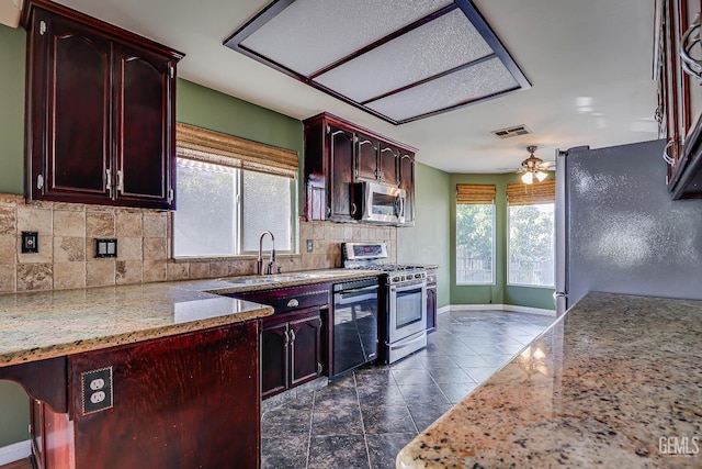 kitchen featuring sink, ceiling fan, backsplash, stainless steel appliances, and light stone counters