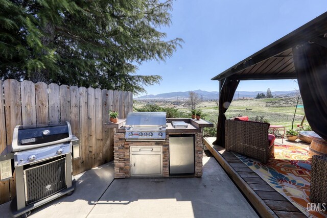 22824 Mariposa Rd, Tehachapi, CA 93561 - view of patio / terrace with a grill, an outdoor kitchen, fence, and a mountain view