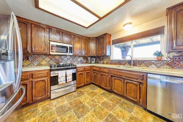 22824 Mariposa Rd, Tehachapi, CA 93561 - kitchen featuring decorative backsplash, a textured ceiling, stone finish floor, stainless steel appliances, and a sink