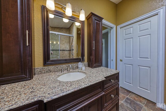 22824 Mariposa Rd, Tehachapi, CA 93561 - bathroom featuring vanity, a textured wall, a shower stall, and stone tile floors