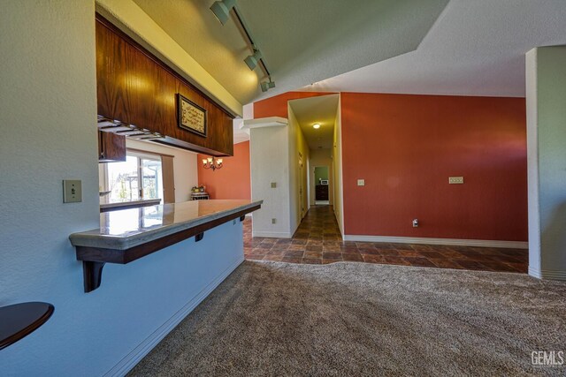 22824 Mariposa Rd, Tehachapi, CA 93561 - kitchen with rail lighting, baseboards, a breakfast bar, and vaulted ceiling