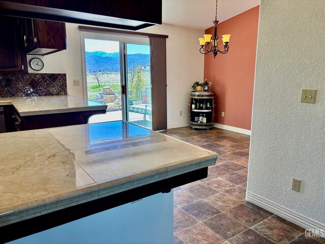 22824 Mariposa Rd, Tehachapi, CA 93561 - kitchen with light countertops, stone tile floors, baseboards, decorative backsplash, and an inviting chandelier